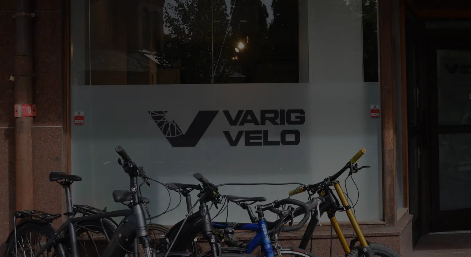 Verkstedvinduet til Varig Velo, med logoen på frostet glass og sykler parkert foran.